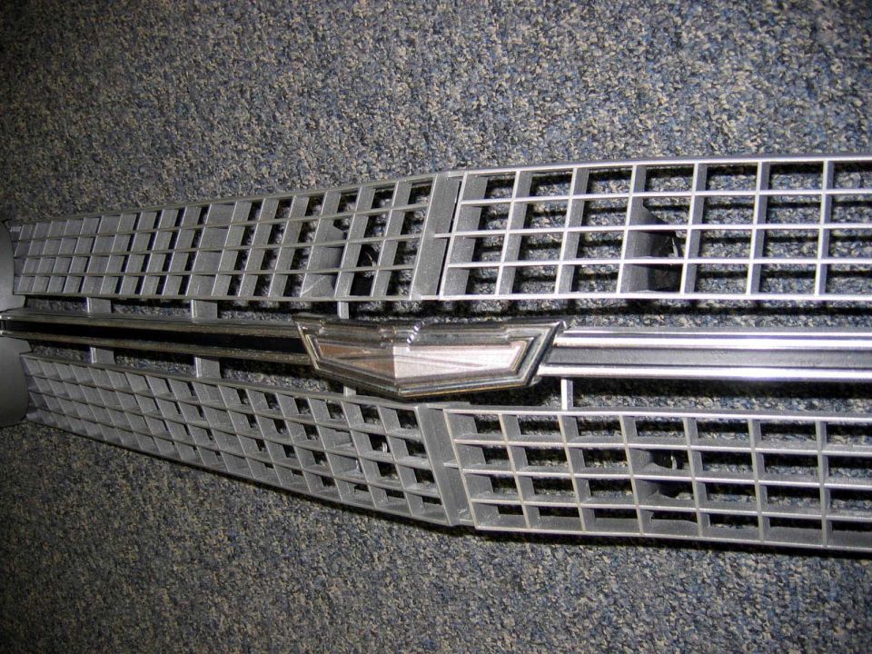 Silver car grille with a chrome emblem and a grid pattern