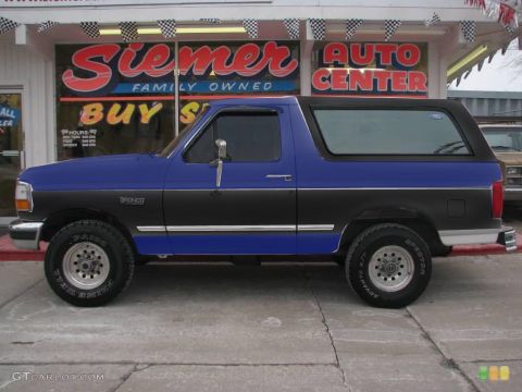 1970 Mercury Cougar - Side view of a two-tone Ford Bronco parked outside a dealership.