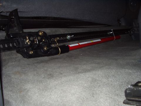 1993 Ford Bronco - A high-lift jack is secured inside a vehicle, with its red handle visible.