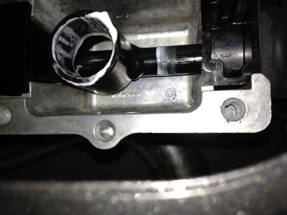 Close-up of an automotive part with white sealant around a hose connection