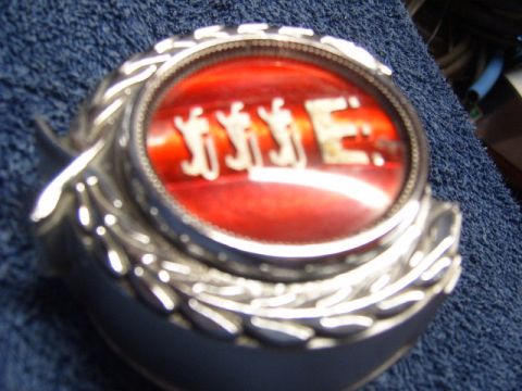 1973 Ford Ranchero - A close-up of a vehicle emblem with a red background and chrome lettering.