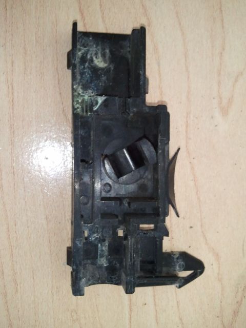 1994 Ford Bronco - This black plastic electrical component features a central circular opening and an external curved lever, likely for a switch or actuator.