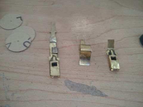 1994 Ford Bronco - Several brass electrical connectors and circular paper pieces with markings are laid out on a wooden surface.