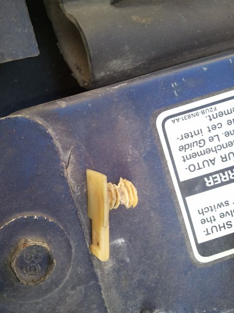 1994 Ford Bronco - Close-up of a plastic fastener and screw on a blue surface, with partial text visible.