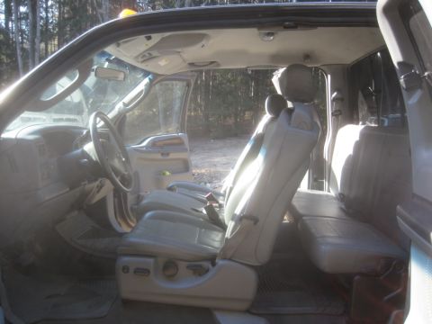 2003 Ford F-350 - The interior of a 2003 Ford F-350 is visible, with light-colored seats and a view of the outdoors through the open doors.