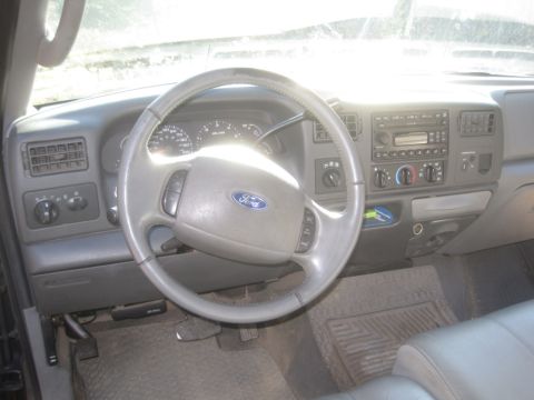 2003 Ford F-350 - The dashboard and steering wheel of a Ford truck are visible, with sunlight streaming through the windshield.