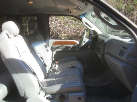 2003 Ford F-350 - The interior of a 2003 Ford F-350 pickup truck features gray leather seats and wood grain trim accents.