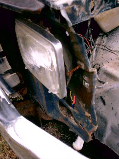 1980 Ford Bronco - Close-up of a damaged headlight and fender area, revealing exposed wiring and rust.