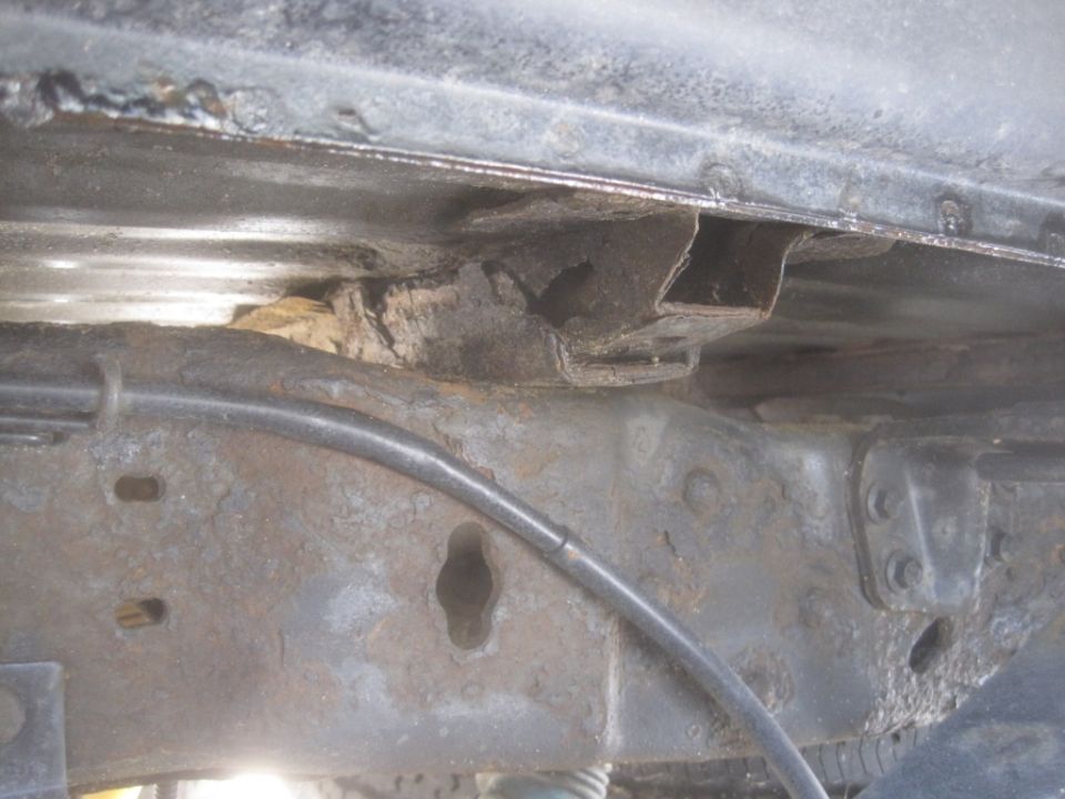 rusted frame section with brake line, showing significant corrosion and damage