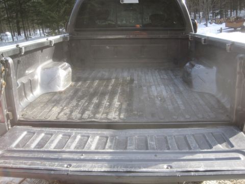 2003 Ford F-350 - The spacious truck bed of a 2003 Ford F-350 pickup, a durable spray-in liner and visible tire well.