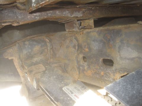 2003 Ford F-350 - Close-up view of heavily rusted frame and suspension parts, with a partial label visible.