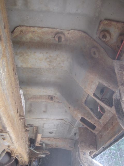 2003 Ford F-350 - The undercarriage of a vehicle shows significant rust and some exposed wiring.