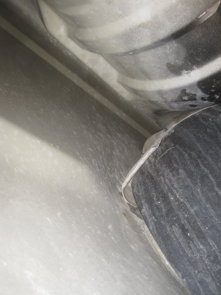 Close-up view of the underbody of a vehicle, showing a black cylindrical component and part of the frame