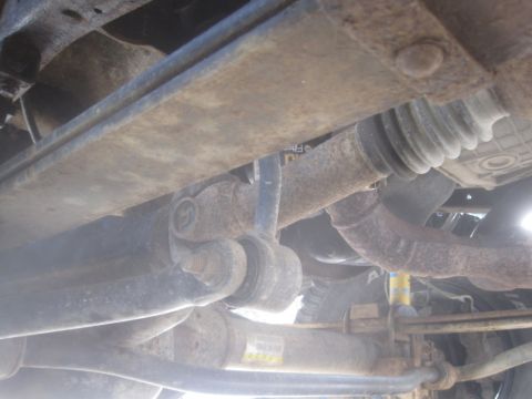 2003 Ford F-350 - Close-up of the undercarriage, showing rusty suspension and drivetrain components.