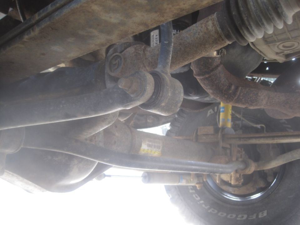 Undercarriage of a truck with rust on suspension components and a yellow Bilstein shock absorber
