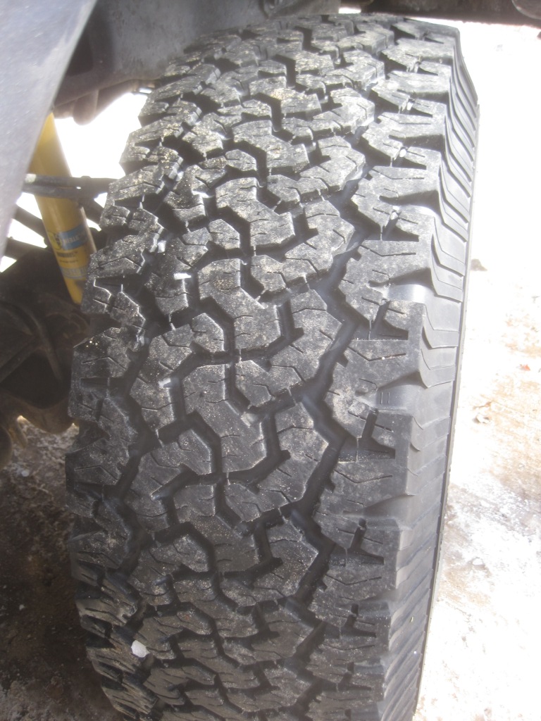 Close-up of a knobby off-road tire tread. Yellow shock absorber visible
