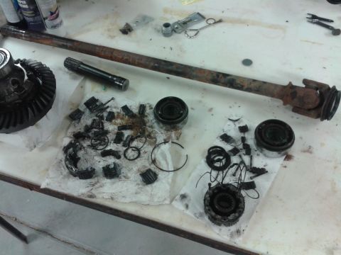 1996 Ford Bronco - Various automotive differential and driveshaft parts are spread out on a table, some showing signs of wear and tear.