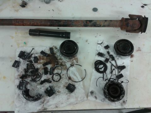 1996 Ford Bronco - Driveshaft and differential parts are laid out on a white surface for inspection or repair.