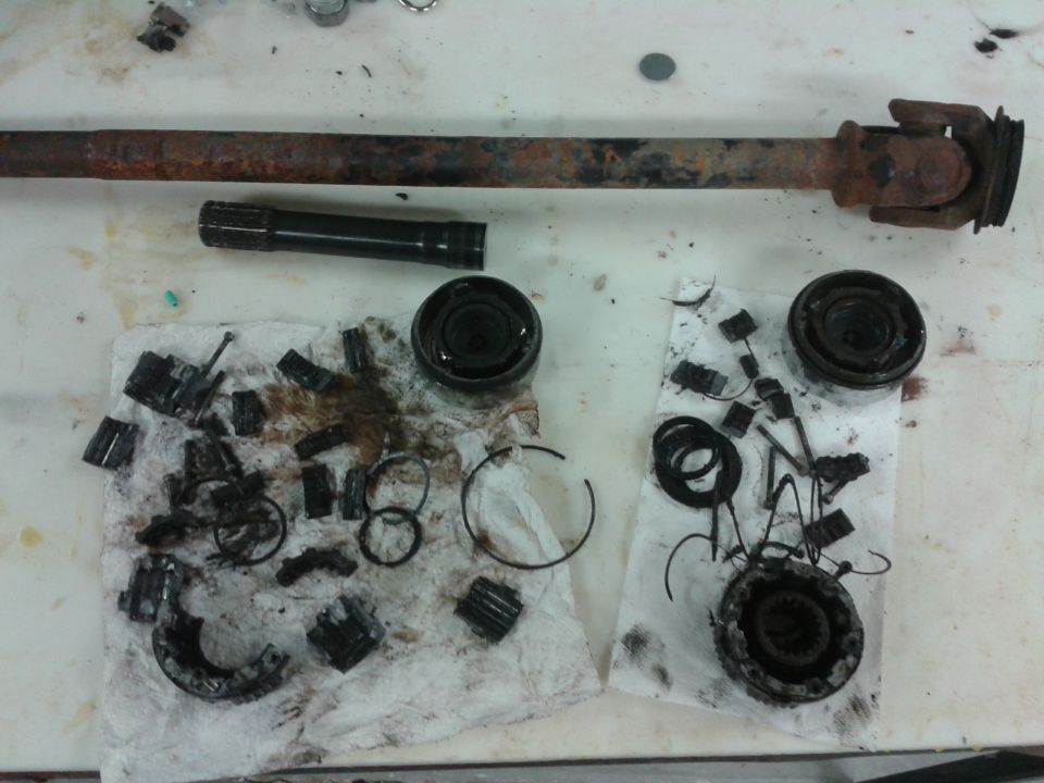 Disassembled driveshaft and differential components on a white surface