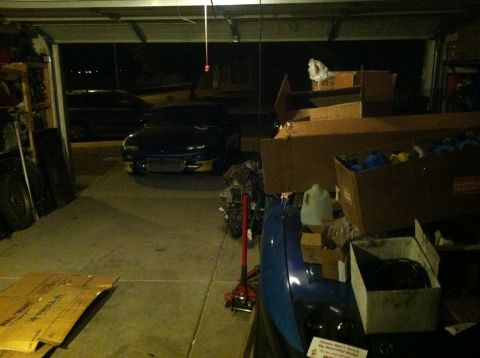 1995 Ford Probe - A blue sports car is parked inside a cluttered garage, with another vehicle visible in the background.
