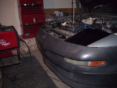 1995 Ford Probe - The engine bay of a 1995 Ford Probe is visible, with a welding machine and tool chest in the background.