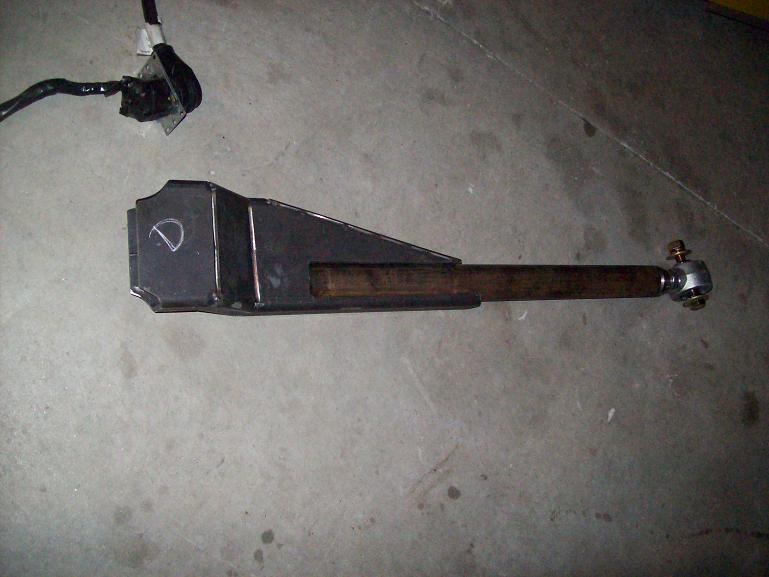 Metal suspension arm with a 'D' marking, resting on a concrete floor