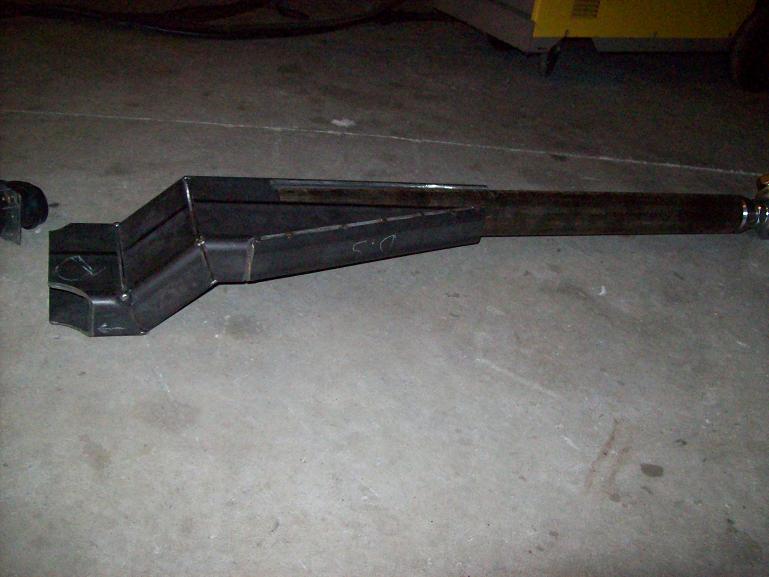 fabricated metal component with angular and cylindrical sections, resting on a concrete floor
