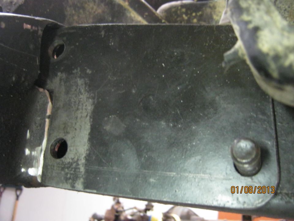 Close-up of a dark metal bracket with two visible bolt holes and a protruding bolt head