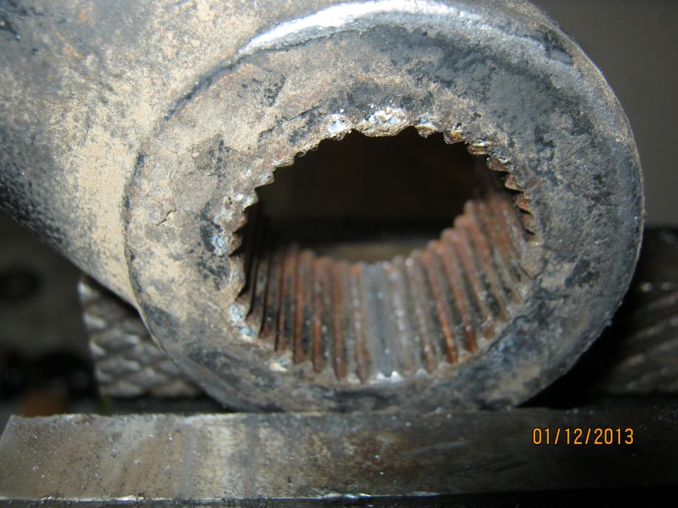 Close-up of a heavily worn, splined metal shaft end held in a vise. Date 01/12/2013 visible