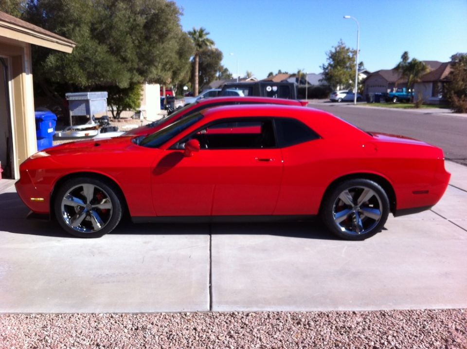 Red Dodge Challenger parked on a driveway, side view