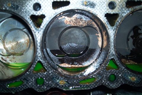 1993 Ford Taurus - Overhead view of three cylinders on a bare engine block deck with the head removed, green coolant standing in the bores and in the coolant…