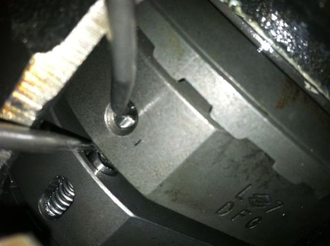 1985 Toyota Pickup/SR5 - A screwdriver is used to turn a screw on a metal engine component.