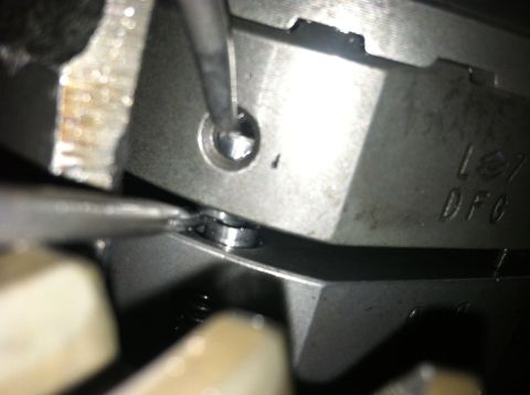1985 Toyota Pickup/SR5 - A mechanic uses a tool on a metal engine part, showing stamped markings.
