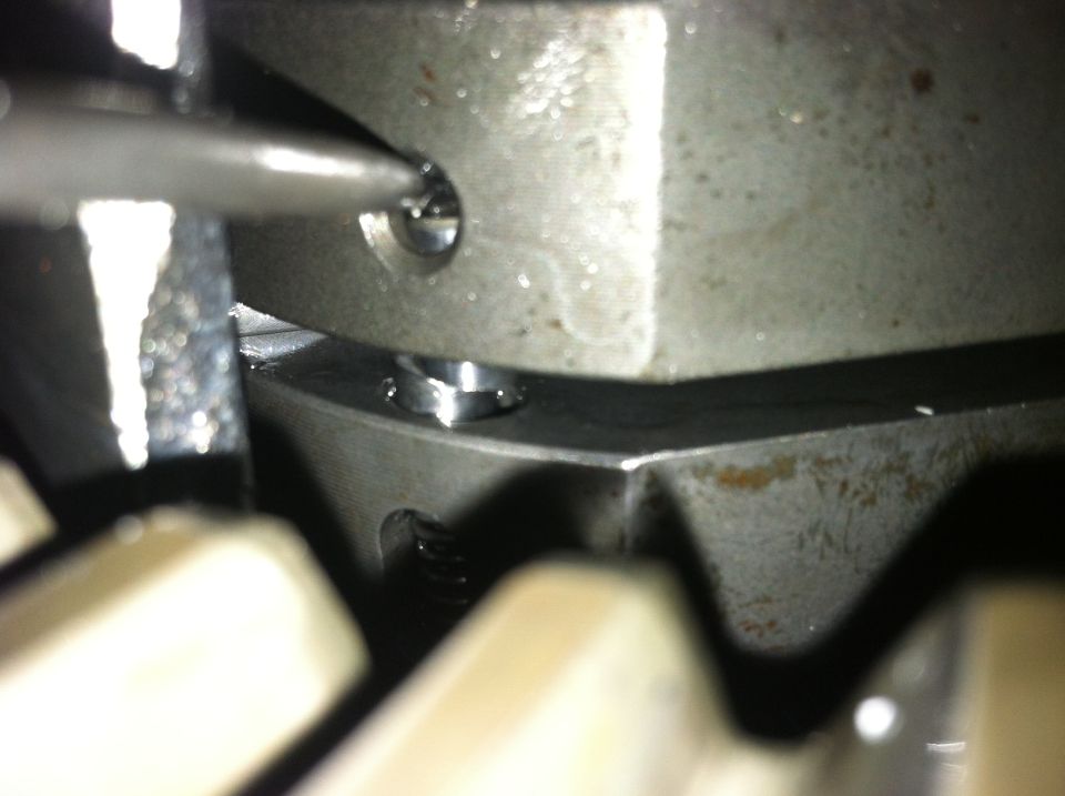 Close-up of metal gears with a screwdriver tip engaging a screw head