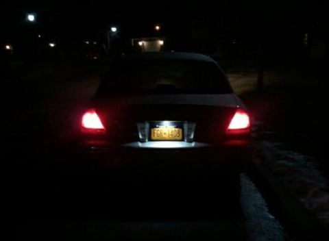 2008 Mercury Grand Marquis - The rear of a sedan is visible at night, with its brake lights and license plate light on.