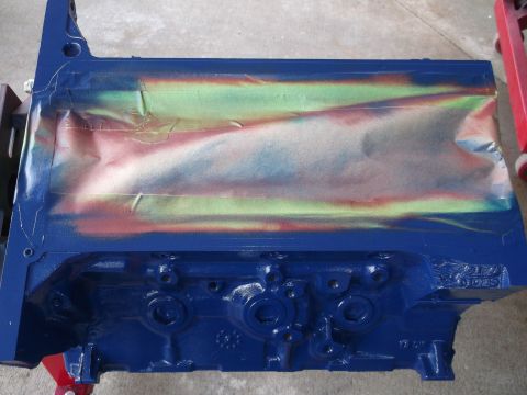1965 Shelby Cobra - A blue engine block is partially covered with masking tape, showing remnants of spray paint in red, green, and yellow hues.