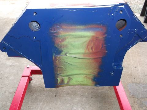 1965 Shelby Cobra - An engine block, partially painted blue, rests on a red stand, revealing underlying green and orange spray paint.
