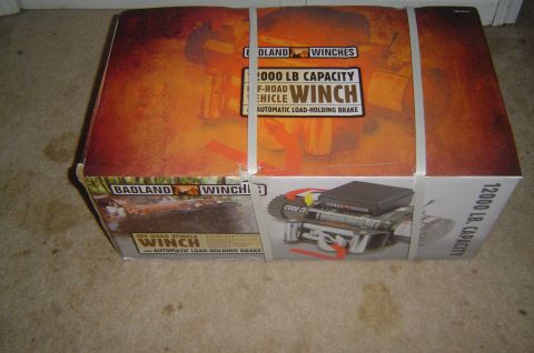 1986 Ford Bronco - A box for a Badland Winches 12000 LB capacity off-road vehicle winch is shown on a carpeted floor.