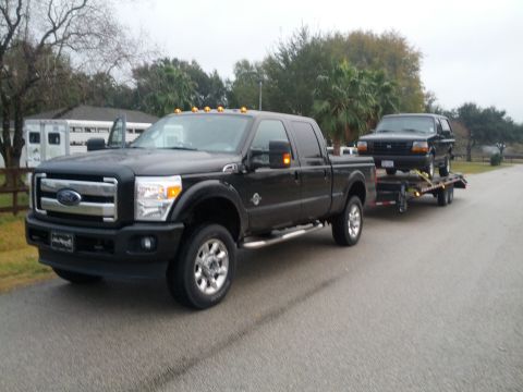 1995 Ford Bronco - A black Ford F-series truck tows a black 1992 Ford Bronco on a trailer.