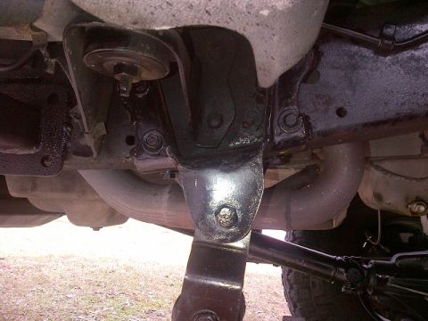 1994 Ford Bronco - Close-up of vehicle suspension and exhaust components, showing a U-joint and mounting brackets.