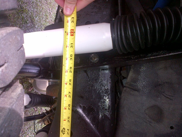 Shock absorber being measured with a tape measure, showing suspension components and a tire
