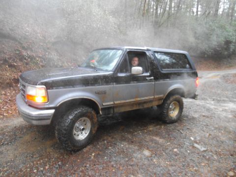 1986 Ford Bronco - Ford Bronco navigates a muddy, wooded trail.