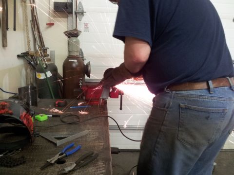 1990 Chevrolet Suburban - A person is using an angle grinder to cut metal, creating a shower of sparks in a workshop setting.