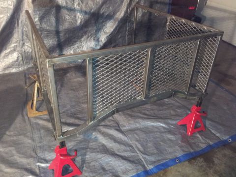 1990 Chevrolet Suburban - A metal trailer frame is elevated on jack stands, resting on a tarp.