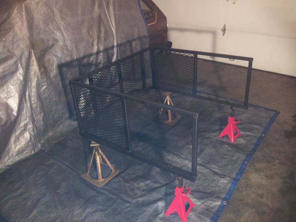 Metal truck bed rack assembly supported by jack stands on a tarp