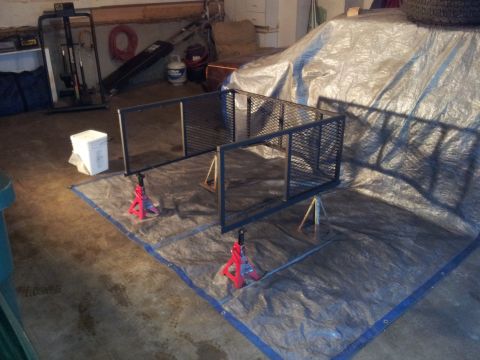 1990 Chevrolet Suburban - A vehicle covered by a tarp is parked in a garage, with a metal rack in the foreground.