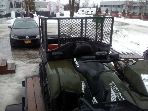 1990 Chevrolet Suburban - An ATV with a cargo rack is parked next to a car in a snowy environment.