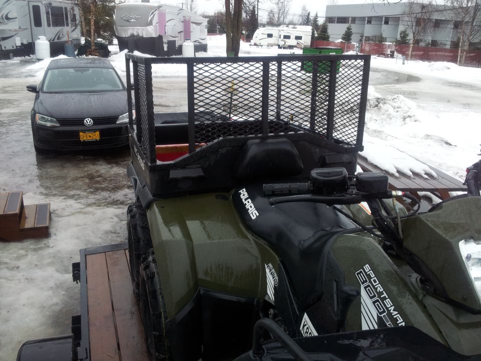 Polaris Sportsman 800 ATV with cargo rack, parked next to a black Volkswagen Jetta in a snowy area