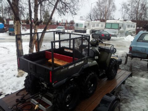 1990 Chevrolet Suburban - An ATV with a cargo bed is loaded onto a trailer in a snowy outdoor setting.
