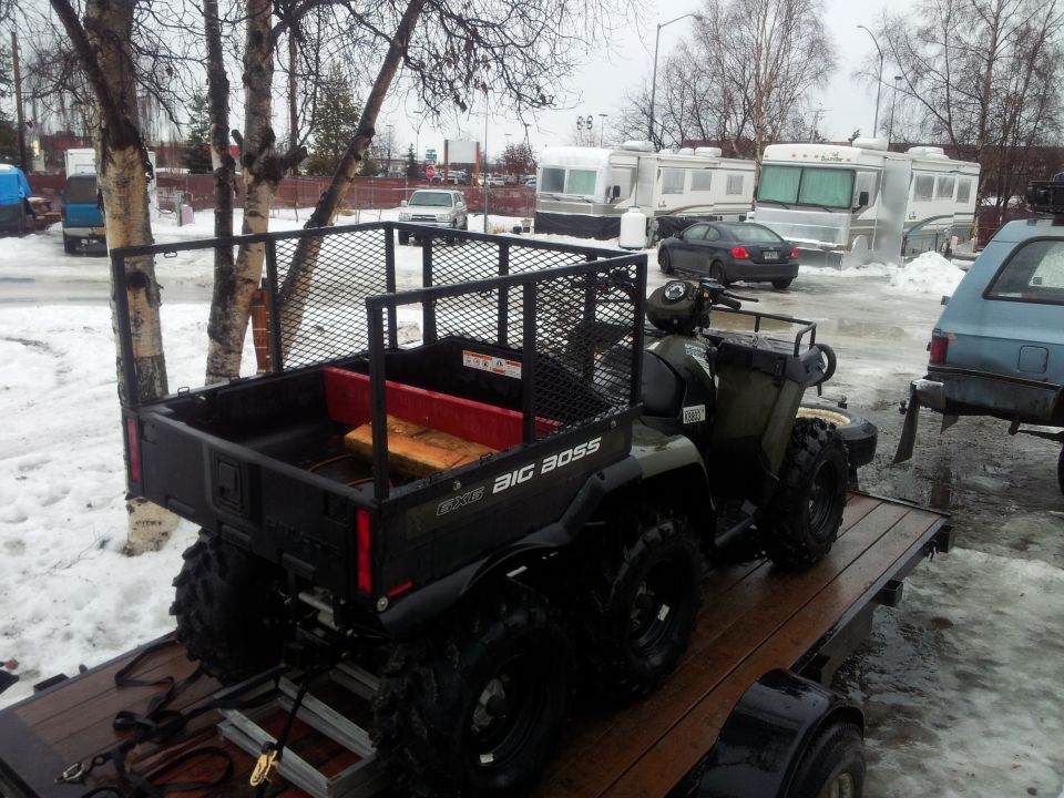 ATV with a cargo bed on a trailer, parked in snow. Text on the side reads 'BIG BOSS'